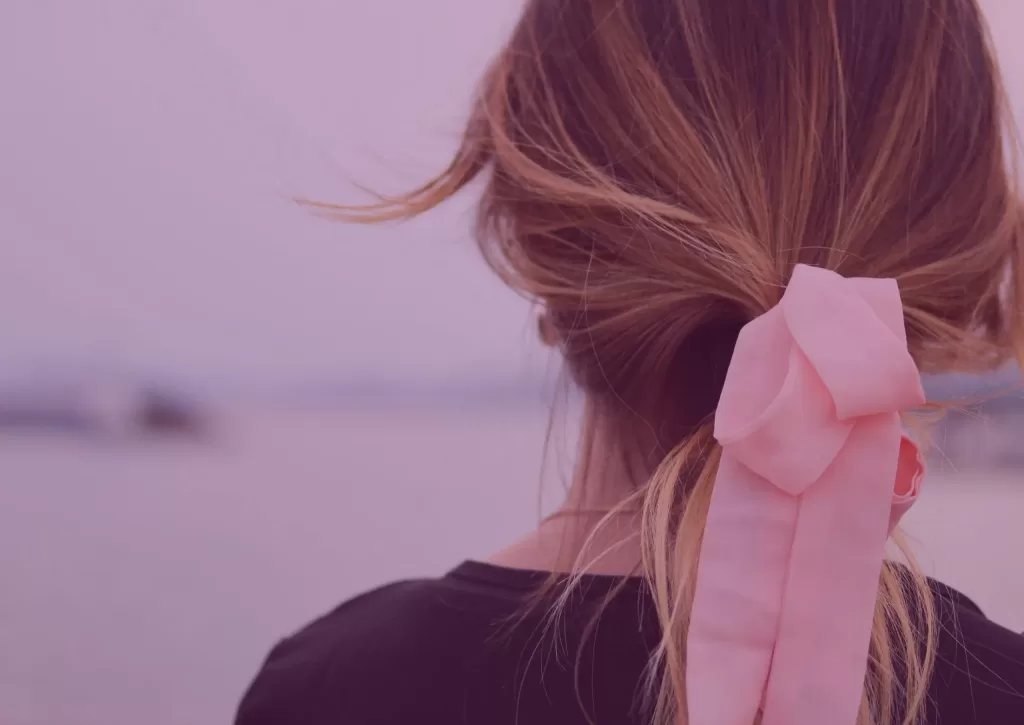 Back of a person's head, with their hair in a pink bow