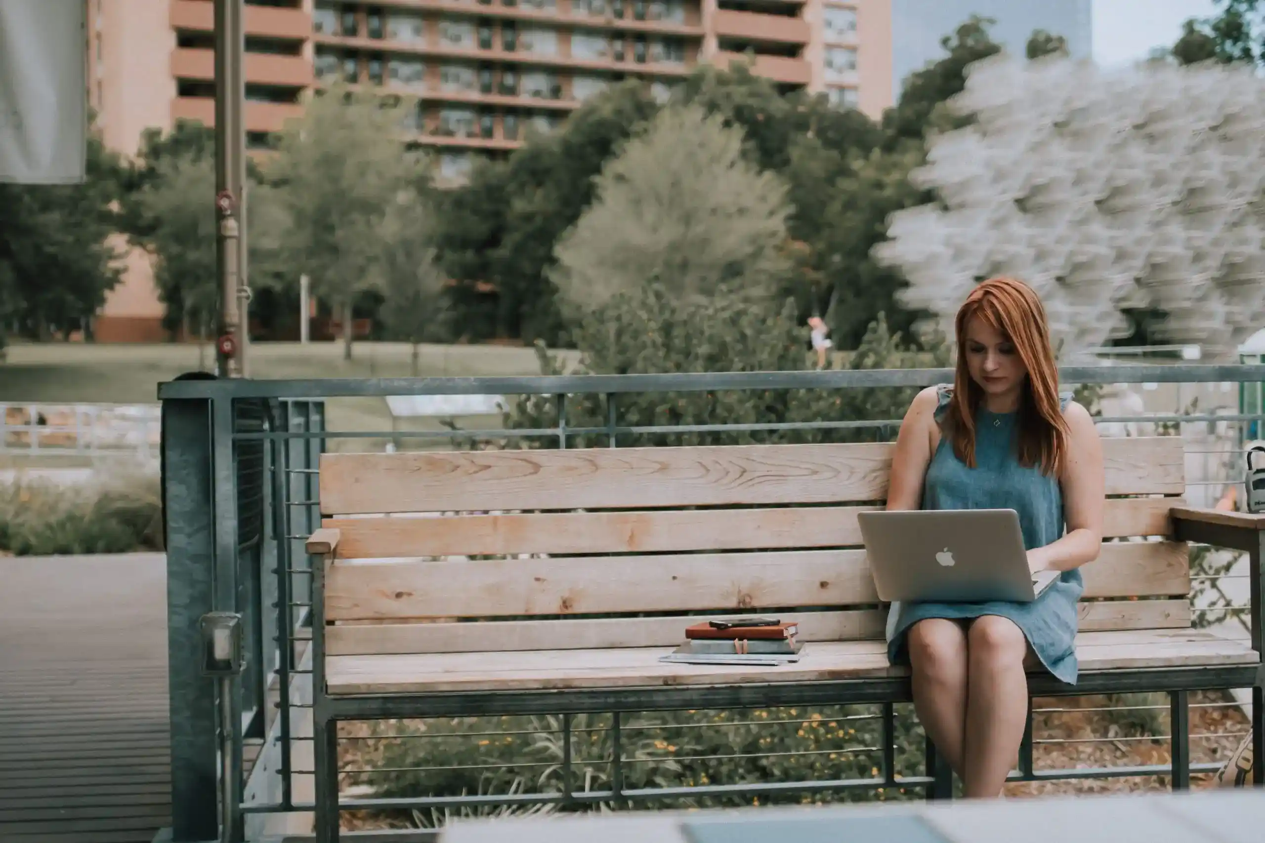 Woman sitting on park bench working on a laptop